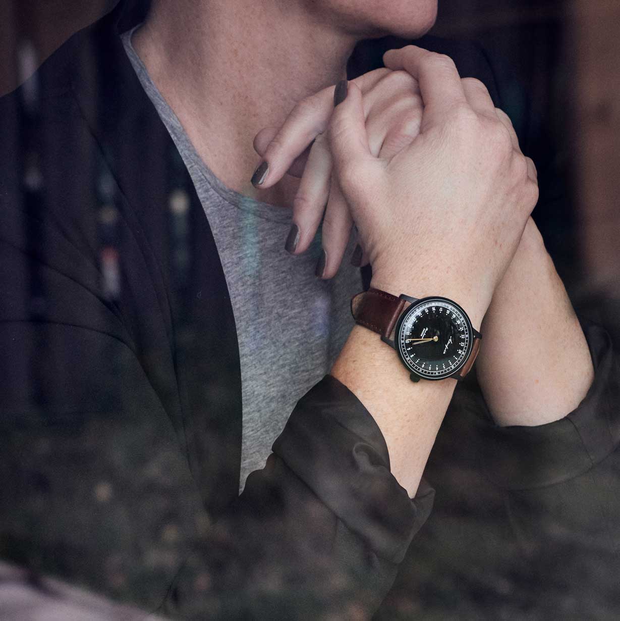 24-hour watch with matte black case and brown leather strap